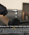 Side view of a black disposable nitrile glove worn by a mechanic gripping a socket wrench near a car.