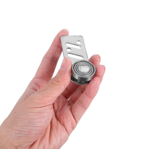 Hand holding stainless steel sliding door pulley with ball bearings, 23mm axle diameter for industrial and warehouse use.