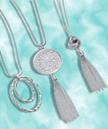 Silver version of six piece long pendant necklace set for women with tassel, knot, disk, and circle designs in gold tone
