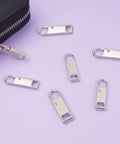 Zipper Pull Replacement Set Six Pack Metal Zipper Handles For Luggage Backpacks Suitcases Jackets Purses And Handbags Easy Clip On Repair Tool No Tools Needed For Everyday Use shown with silver zipper pulls.