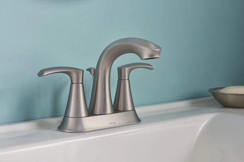 Graeden Two Handle Four Inch Centerset Bathroom Faucet in Spot Resist Brushed Nickel on white sink with blue wall background