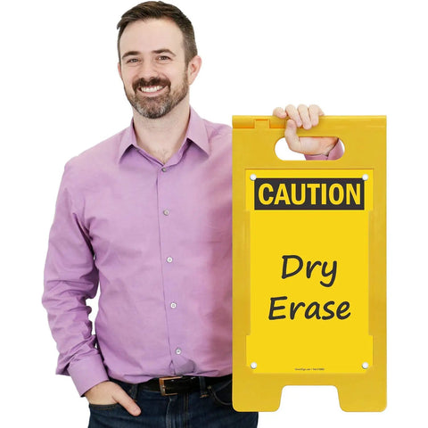 Blank Caution Folding Floor Sign 25 By 12 Inches Double Sided Dry Erase Plastic Sign With Built In Handle Write On Surface Grab And Go Portable Durable Great For Temporary Hazards And Safety Messages. Man holding yellow dry erase caution floor sign with handle