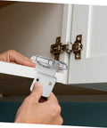 Inset cabinet hinge, chrome finish, installed on white cabinet door.