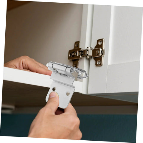 Inset cabinet hinge, chrome finish, installed on white cabinet door.