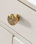 Durable Zinc Alloy Vintage Cabinet Knobs Five Pack - Antique Brass Drawer Pulls Art Deco Star Detail 1 1/8 Inch on white drawer.