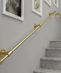 Badass Wrought Iron Handrail For Stairs Indoor And Outdoor Wall Mount Grab Bar in gold finish on gray wall and stairs.
