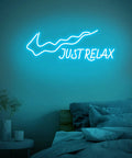 Just Relax LED Neon Sign For Walls USB Powered Light Up Decor with on off switch in ice blue, mounted above a bed.