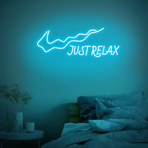 Just Relax LED Neon Sign For Walls USB Powered Light Up Decor with on off switch in ice blue, mounted above a bed.