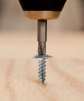 Close-up of a #8 Phillips truss head screw being driven into wood using a power drill from Knockout Value 95 Piece Assortment Kit.