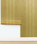 Top Tier Weathered Stripe Gold Metallic Wallpaper For Dope Indoor Walls Featuring Hella Stylish Fibrous Texture And Paste The Wall Application With Eco Friendly Pvc Free Class A Rated Finish That Adds Serious Swag To Any Room Setup displayed on a wall with a light wood floor.