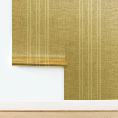 Top Tier Weathered Stripe Gold Metallic Wallpaper For Dope Indoor Walls Featuring Hella Stylish Fibrous Texture And Paste The Wall Application With Eco Friendly Pvc Free Class A Rated Finish That Adds Serious Swag To Any Room Setup displayed on a wall with a light wood floor.