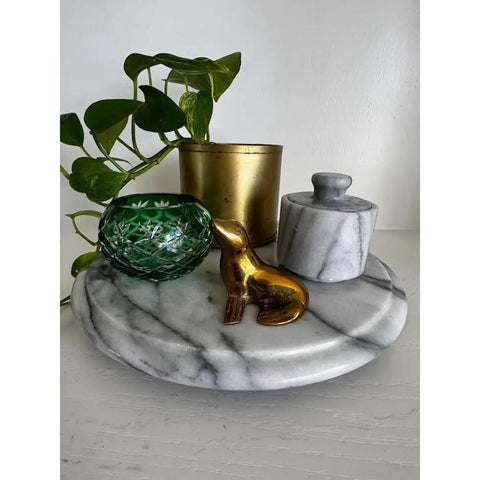 11.75 Inch Marble Lazy Susan Turntable With Vintage Gray Stone Finish, holding decor items and plant, on a table.