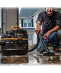 Man using Beast Series 5 Gallon Wet Dry Vacuum With 5.5 HP Motor, 1-7/8 Inch Hose for cleaning wet surface in garage.