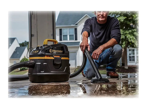 Man using Beast Series 5 Gallon Wet Dry Vacuum With 5.5 HP Motor, 1-7/8 Inch Hose for cleaning wet surface in garage.