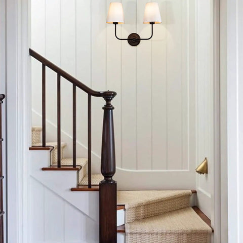 Hardwired 2 Light Dual Lamp Modern Armed Wall Sconce With Flared White Fabric Shades in stairway with white walls.