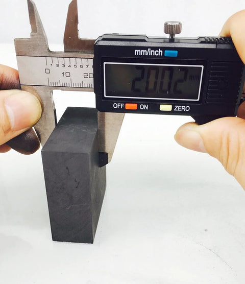 Measuring 50 mm x 50 mm x 20 mm high purity 99.9 percent graphite ingot block for EDM milling use with calipers