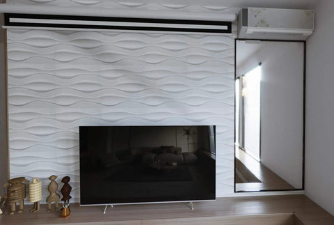 Wave Wall Panels 19.7 Inch Square Pack Of 12 White PVC Panels For Living Room And Kitchen DIY Friendly Fire Resistant Lightweight 32 Sq Ft Coverage For Home Use displayed behind a TV on a living room wall.