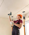 Get The Crew With This Adjustable Cabinet Jack Support Pole, a worker using a drill for drywall installation.
