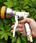 Person holding Heavy Duty Metal Hose Nozzle Sprayer With 7 Spray Patterns For High Pressure Watering And Car Wash against greenery
