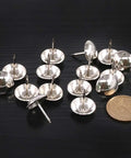 Badass Rock Solid 200 Piece Antique Upholstery Tacks And Furniture Nails Pin Assortment Kit In Classic Silver scattered with a coin for size reference.