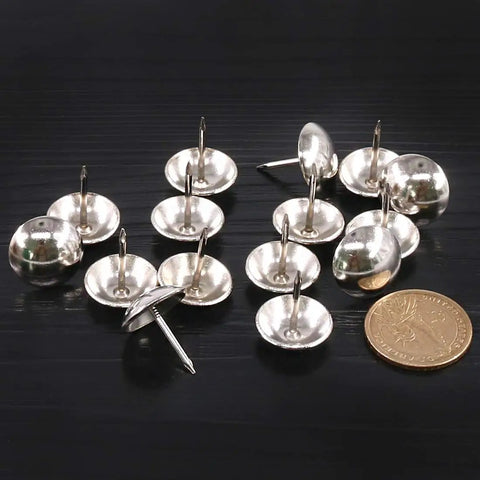 Badass Rock Solid 200 Piece Antique Upholstery Tacks And Furniture Nails Pin Assortment Kit In Classic Silver scattered with a coin for size reference.