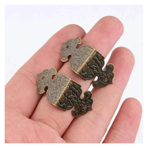 50 Piece Antique Bronze Corner Brackets and Protectors for Furniture Edges in hand, showing vintage brass detail