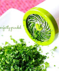 Cilantro And Spice Grinder Manual Stainless Steel Green Easy Clean Kitchen Tool grinds herbs above white surface