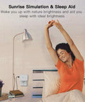Dimmable Smart Plug 2 Pack With Sunrise And Sunset Simulation in bedroom, showing woman stretching near bedside lamp.