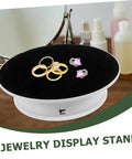 Rotating Electric Turntable Display Stand With Smooth Motorized Motion showcasing gold rings and pink earrings on black surface.
