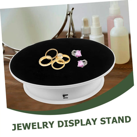 Rotating Electric Turntable Display Stand With Smooth Motorized Motion showcasing gold rings and pink earrings on black surface.