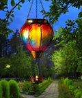 Hot Air Balloon Solar Lantern With Candle Holder Lit Flickering Flame Hanging Outdoor Garden Light in a tree at dusk