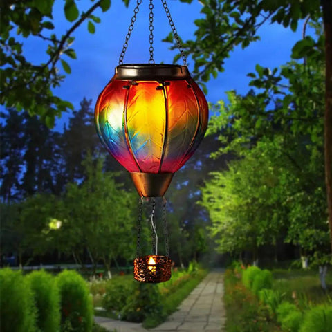 Hot Air Balloon Solar Lantern With Candle Holder Lit Flickering Flame Hanging Outdoor Garden Light in a tree at dusk