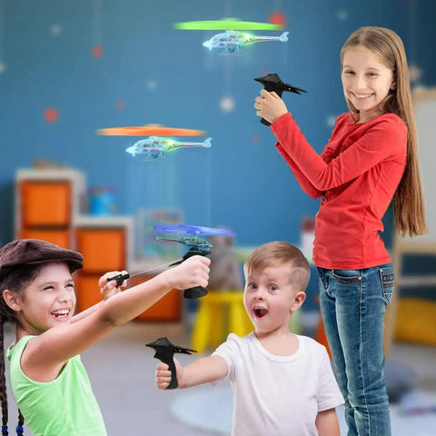 Kids playing with Light Up Flying Helicopters Set Of 2 With LED Lights And Handheld Launcher, soaring over eight feet indoors