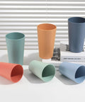 12 Piece Wheat Straw Cups Set With 6 Colorful 12 Oz Cups And 6 Colorful 20 Oz Cups Unbreakable BPA Free Reusable Plastic Drinking Cups For Outdoor Camping Kitchen Use Microwave And Dishwasher Safe Built Tough For All Your Adventures displayed on a white surface with a book in the background