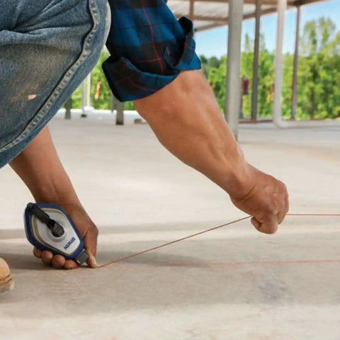 Worker using Speedline Pro Chalk Reel 100 Foot Hi Tensile Line With Easy Fill Lock Top Three To One Gear Rewind on rough surface