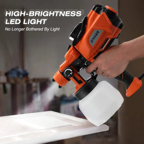 Hand using Powerful 800W HVLP Electric Paint Sprayer with LED Light, 1200ml cup, orange body, spraying on white surface