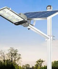 Ultra Bright 1000W Solar Street Light With 765 LEDs Dusk To Dawn Outdoor Pole Light on white pole with solar panel in garden setting.