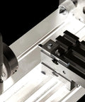 Front view of a miniature metal lathe; cross-slide carriage with T-slots on a silver bed.