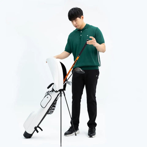 Man holding Golf Swing Trainer Pro Indoor Practice Aid with MAX SPEED Stick next to golf bag in studio setting.
