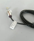 Front view of M12 normally open proximity sensor with cable, metal threaded body; magnet shown nearby