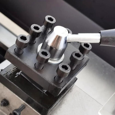 Metal lathe tool post assembly on bench lathe, black base with six hex-socket screws and silver knob