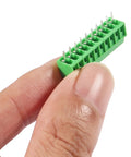 Hand holding a green 10 Pack 10Pin 2.54mm 0.1 Inch Pitch PCB Screw Terminal Block Connectors 150V 6A For 26 To 18 AWG Cable ABS Plastic Housing
