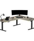 Rock Solid Electric L Shaped Standing Desk 78 By 60 Inches Triple Motor Sit Stand Corner Table with laptop and monitor setup.
