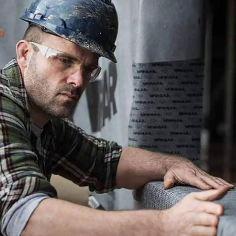 Construction worker applying flexible peel and stick flashing for windows and doors on a building surface