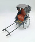 Heavy Duty Alloy Vintage Rickshaw Model With Old School Charm And Historical Precision Solid Metal Antique Tricycle Figurine for desk display, featuring a red seat and black canopy.