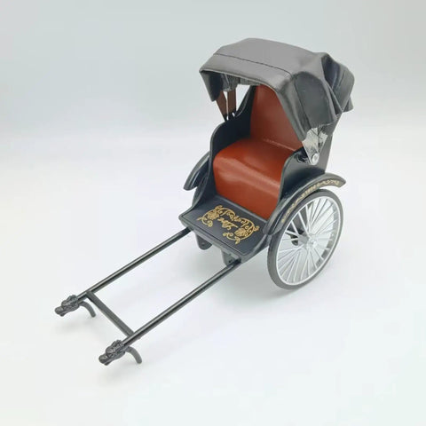 Heavy Duty Alloy Vintage Rickshaw Model With Old School Charm And Historical Precision Solid Metal Antique Tricycle Figurine for desk display, featuring a red seat and black canopy.