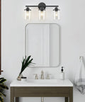 Three Light Matte Black Vanity Light With Clear Glass Shades For Bathroom above a modern sink and mirror