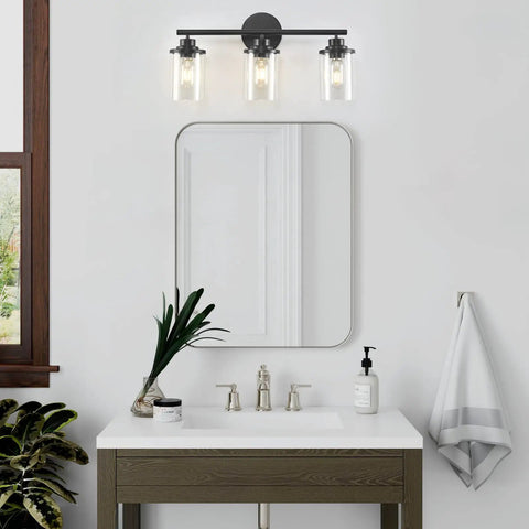 Three Light Matte Black Vanity Light With Clear Glass Shades For Bathroom above a modern sink and mirror