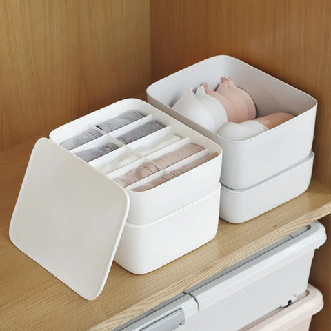 Stackable White Plastic Drawer Organizers For Bras Socks And Underwear Open Top Storage Bins on wooden shelf with sorted items.