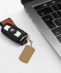 Rock Solid Large Grid Weave Jute Texture Rectangle Plated Metal Keychain next to a laptop key, showcasing daily carry versatility.
